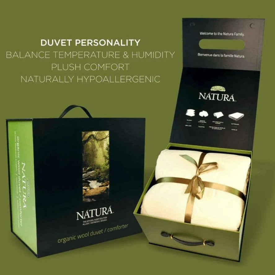 NATURA organic wool duvet cover set shown in its packaging against an olive green background. The image features a closed black and green gift box on the left, and an open matching box on the right displaying a folded cream-colored duvet cover tied with a gold ribbon.